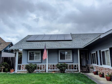 house with all black solar panels and an american flag out front